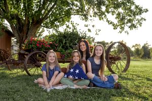 Candid group photo in natural outdoor setting with rustic farm elements and flowering bushes.