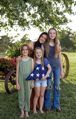 Group portrait in casual summer outfits standing together outdoors with trees and greenery in background.