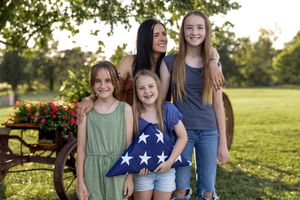 Casual outdoor portrait with American flag shorts and summer clothing in a grassy field.