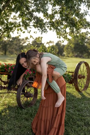 Playful outdoor portrait session with vintage farm equipment and summer greenery.