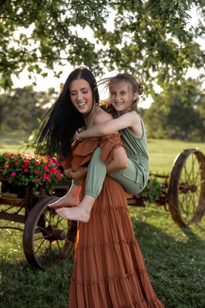 Joyful outdoor moment captured against pastoral background with antique wagon wheel.