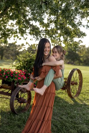 Natural candid moment shared outdoors with rustic farm elements and summer foliage.