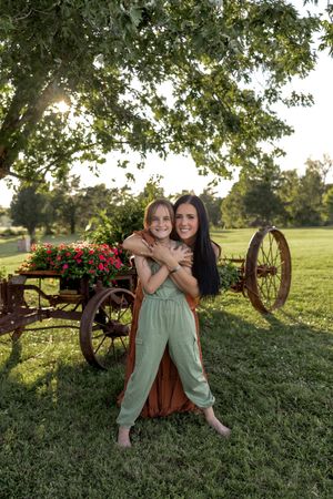 Joyful outdoor portrait in front of an antique wagon decorated with vibrant red flowers.