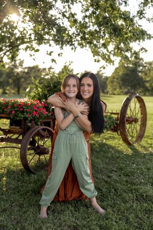 Warm sunset lighting illuminates a tender moment in front of a rustic garden wagon display.