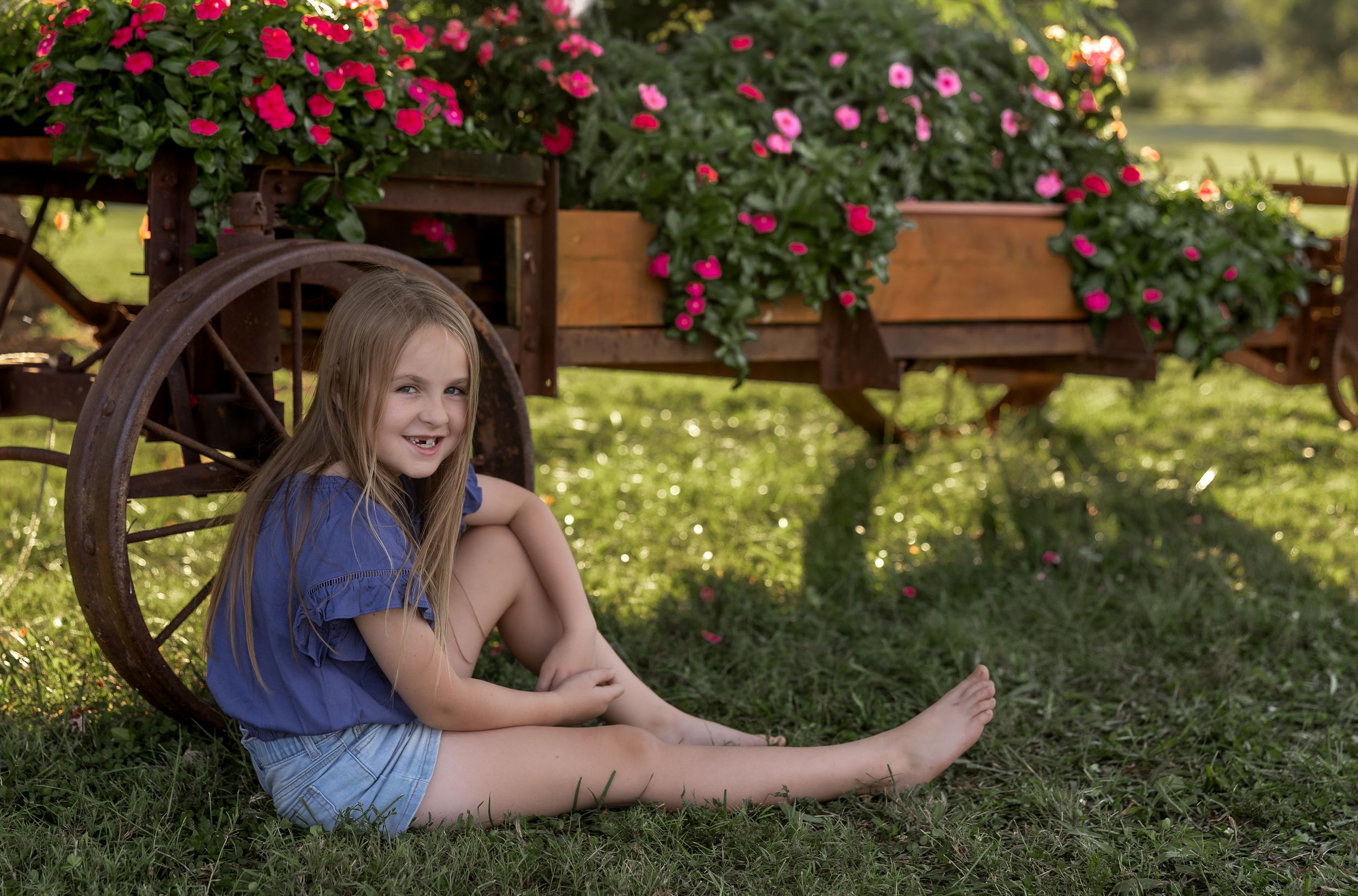 Casual outdoor portrait session in garden setting with red flowers and natural lighting.
