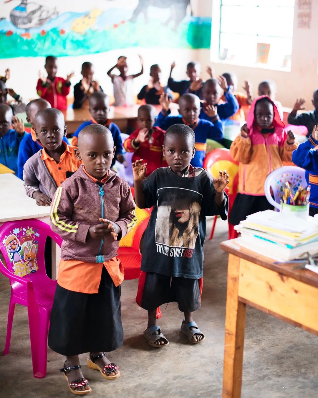 Children gather in a community hall for a local education and nutrition programme supporting early childhood development.