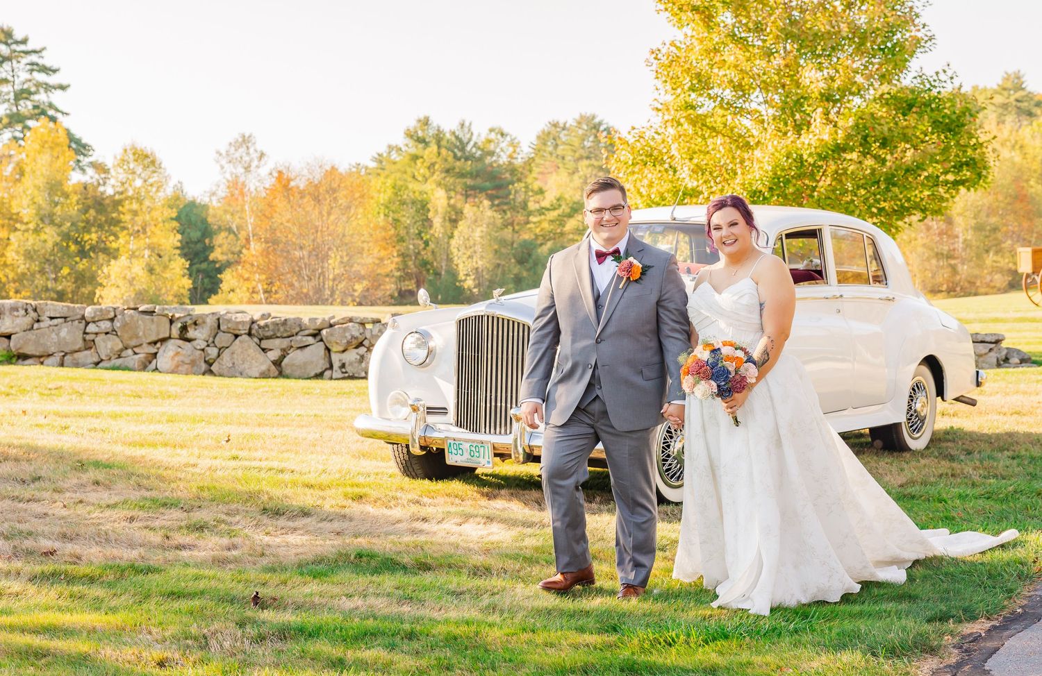 A couple poses near a vintage pickup truck in a rustic outdoor setting during golden hour.