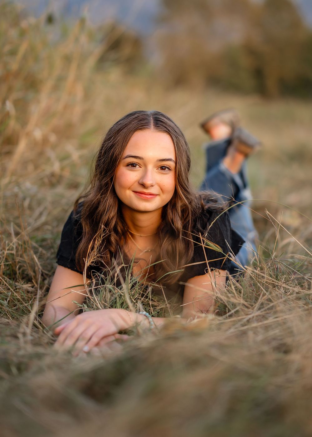 Natural outdoor portrait session in tall dry grass with soft lighting and shallow depth of field.