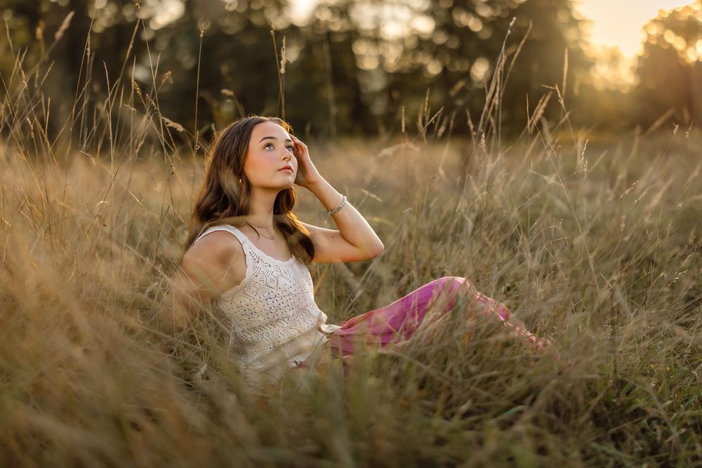 Dreamy sunset portrait session in flowing white dress among tall grass.