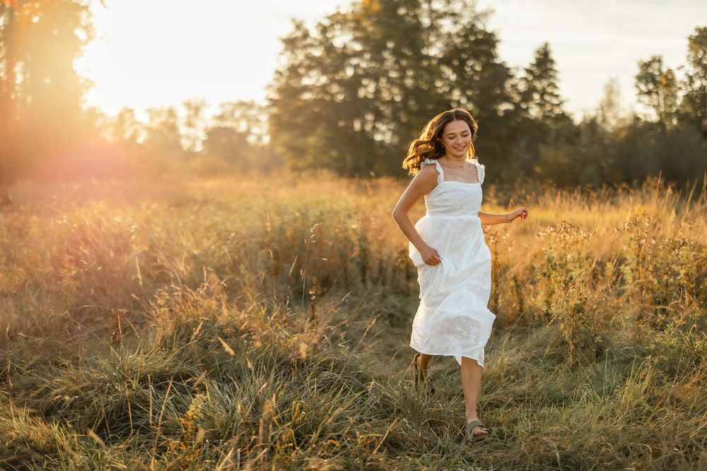 Golden hour sunset illuminates mountain meadow with flowing dress movement.