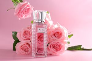 parfum Miss Dior Rose N’Roses devant un bouquet de roses roses sur fond rose photographie de produit élégante réalisée par un photographe