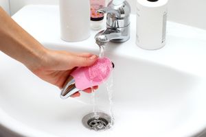 Cepillo facial de silicona rosa enjuagado bajo el grifo, con botones de intensidad y acabado metálico fotografía de producto España Bilbao