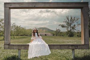 Niña de Comunión sentada en el césped con vestido blanco y ambiente natura, parque Olarizu, fotógrafa en Vitoria