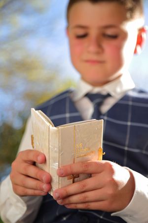 Retrato artístico de niño con fondo desenfocado en la naturaleza con biblia, fotógrafa de primera comunion, Vitoria, Bilbao, Donosti
