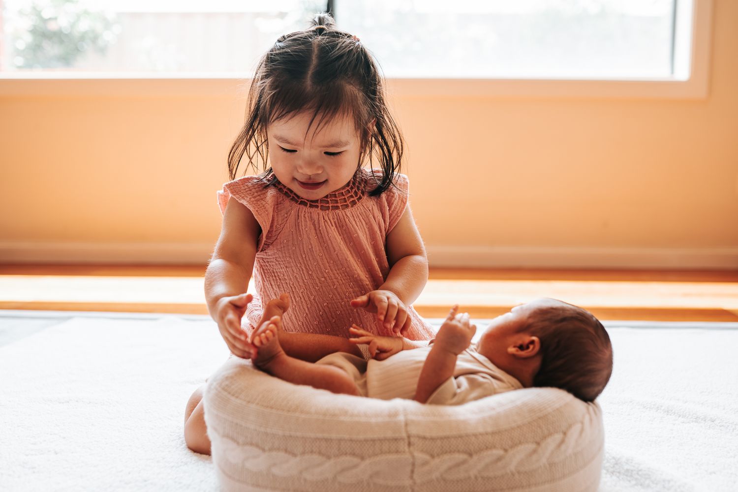 Elder sister holding her newborn sister hands taken by a Melbourne newborn photographer.