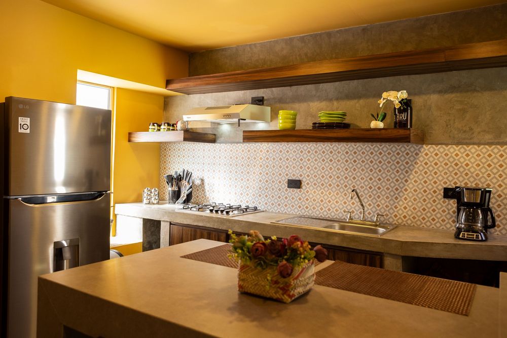 Modern kitchen interior with yellow walls, dark wood cabinets, and stainless steel appliances.
