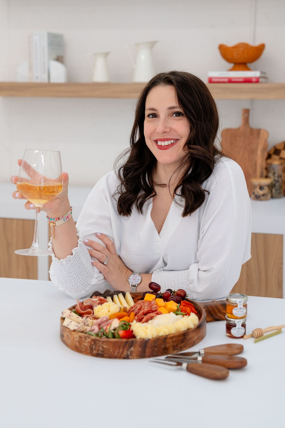 A series of lifestyle photos showing a white marble counter with charcuterie boards and wine glasses in a bright kitchen setting.