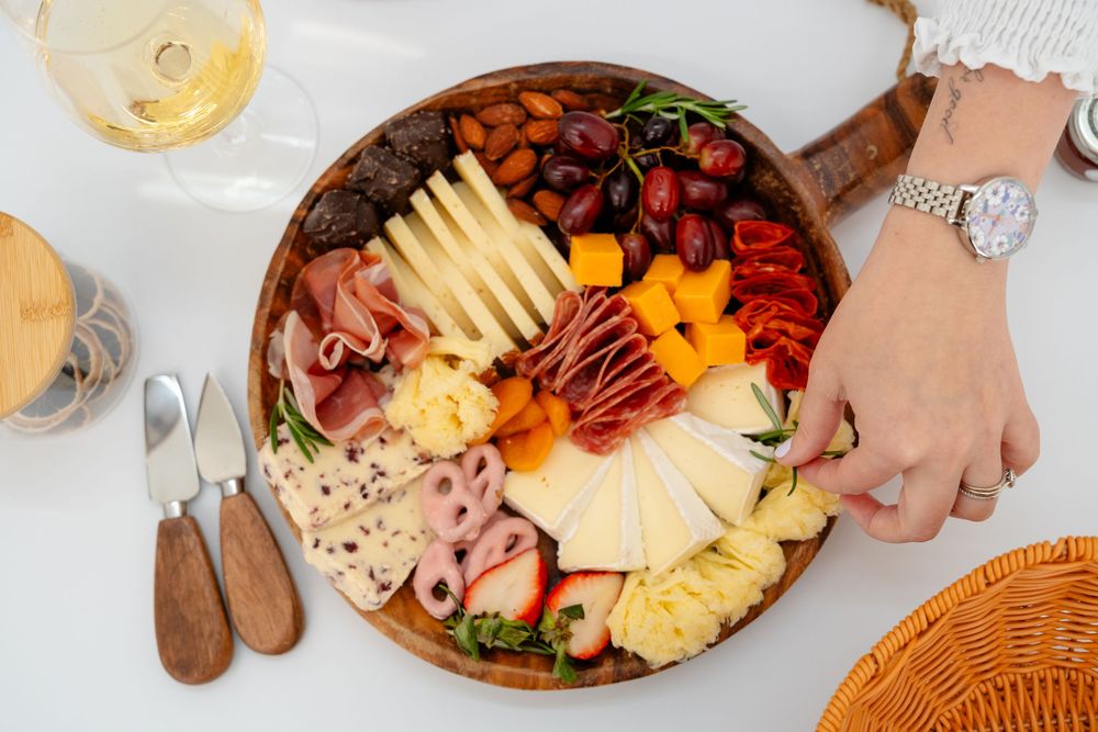 A rustic wooden charcuterie board with an assortment of cheeses, meats, and fruits arranged beautifully.