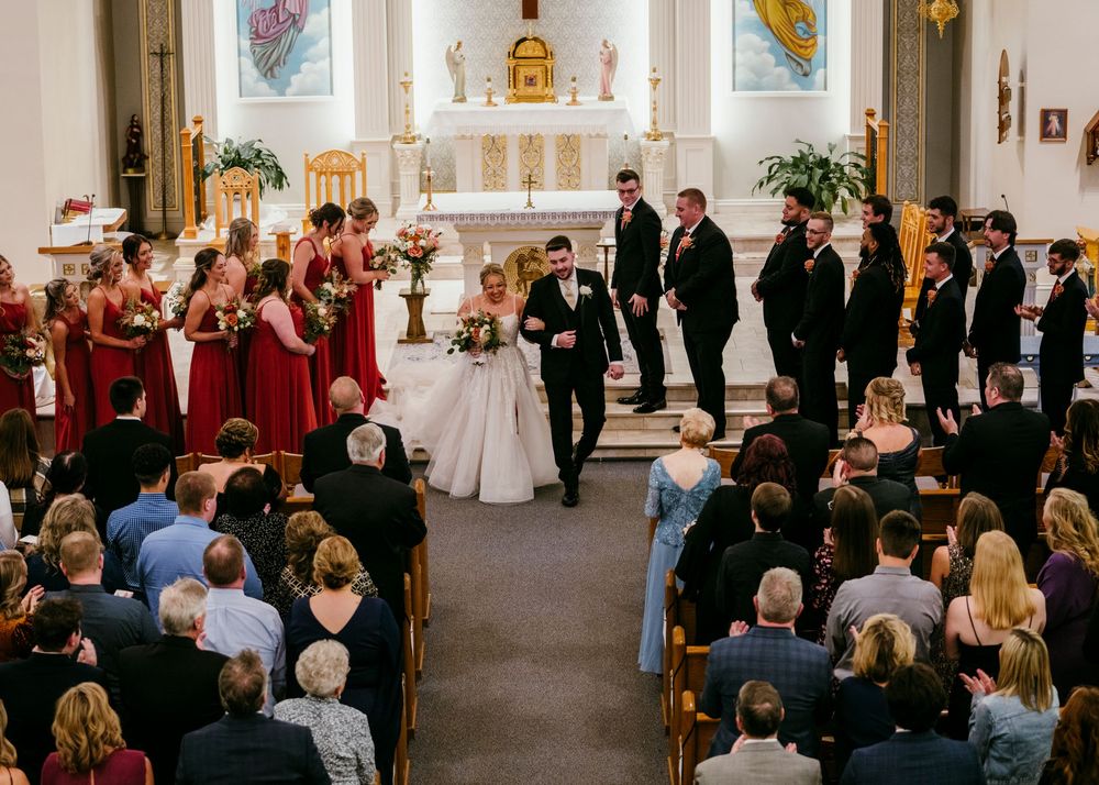 Church wedding ceremony with guests seated in pews and decorative stained glass windows.