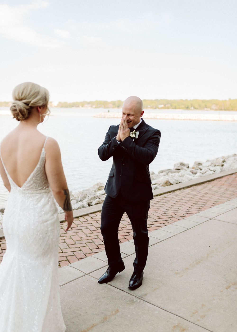 First look wedding moment captured on a brick pathway by the waterfront.