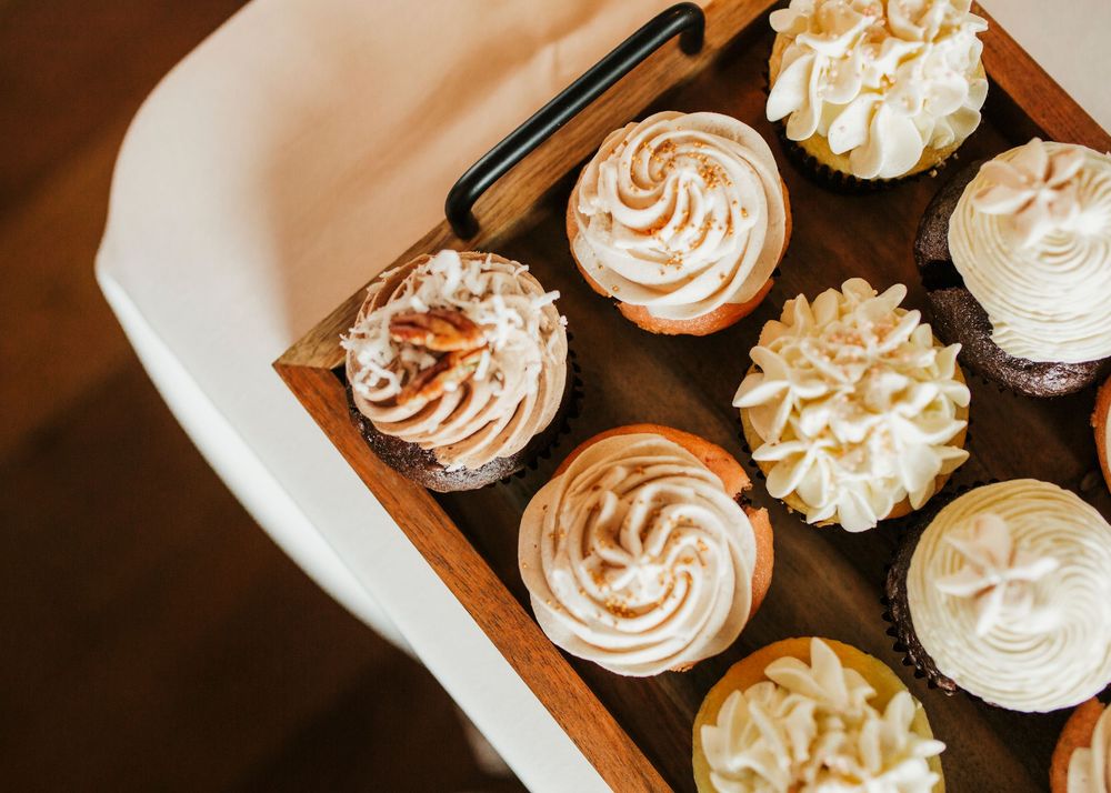 Artfully decorated cupcakes with swirled frosting displayed on a wooden board.