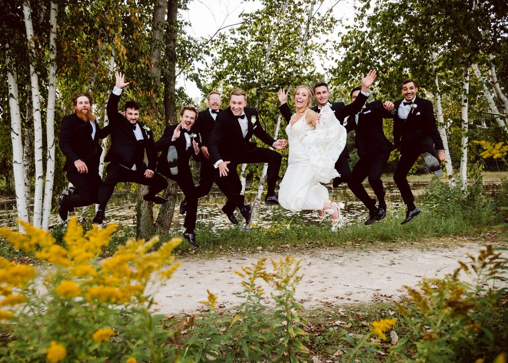 Wedding party jumps joyfully on path surrounded by aspen trees and wildflowers.
