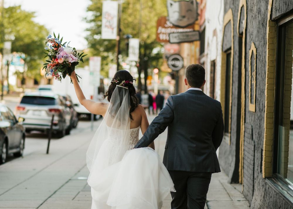 Newlyweds walking together on a city sidewalk during their wedding day.
