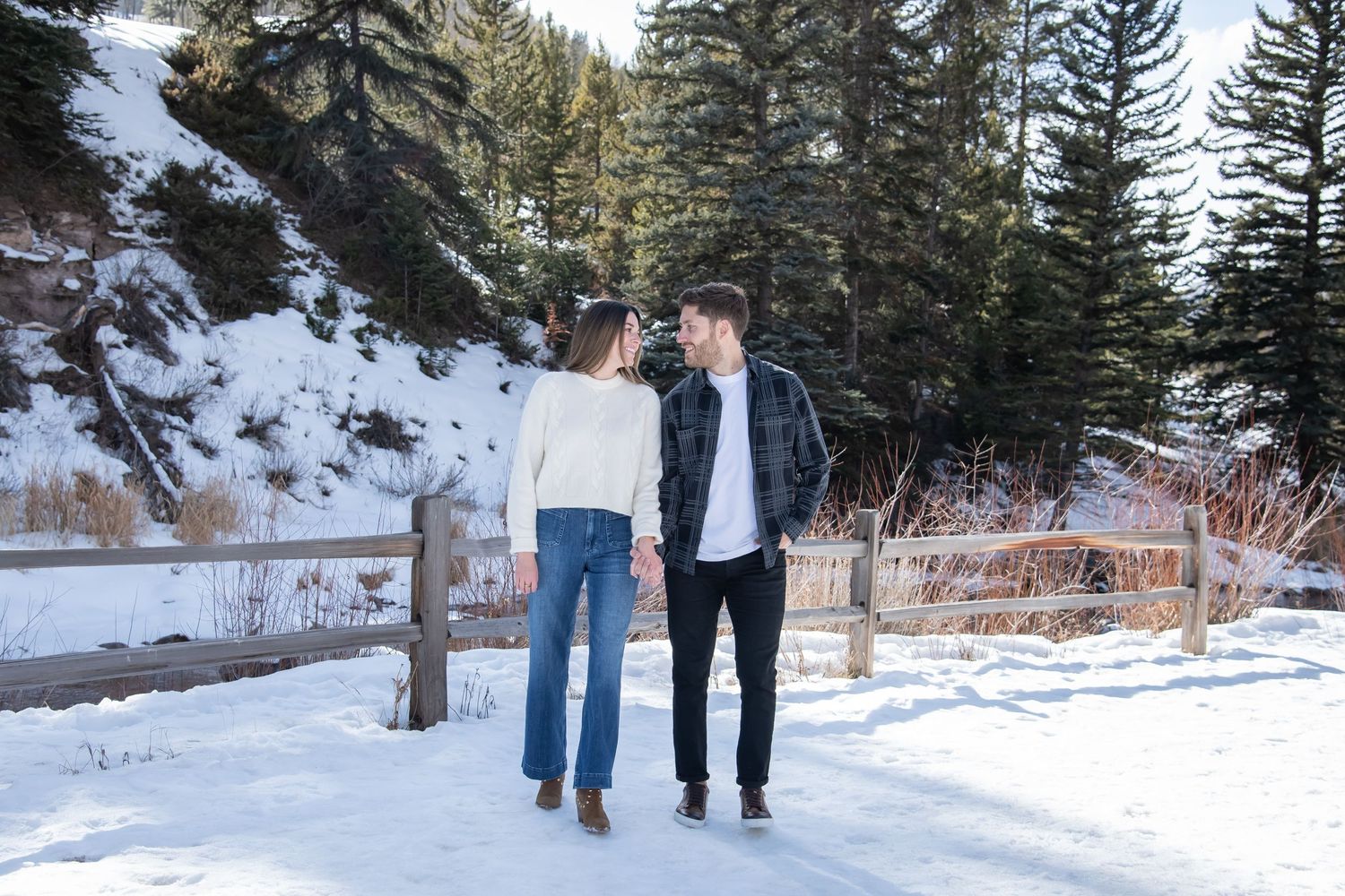 A stylish couple walks together in the snow during their winter engagement photo session in Vail Colorado