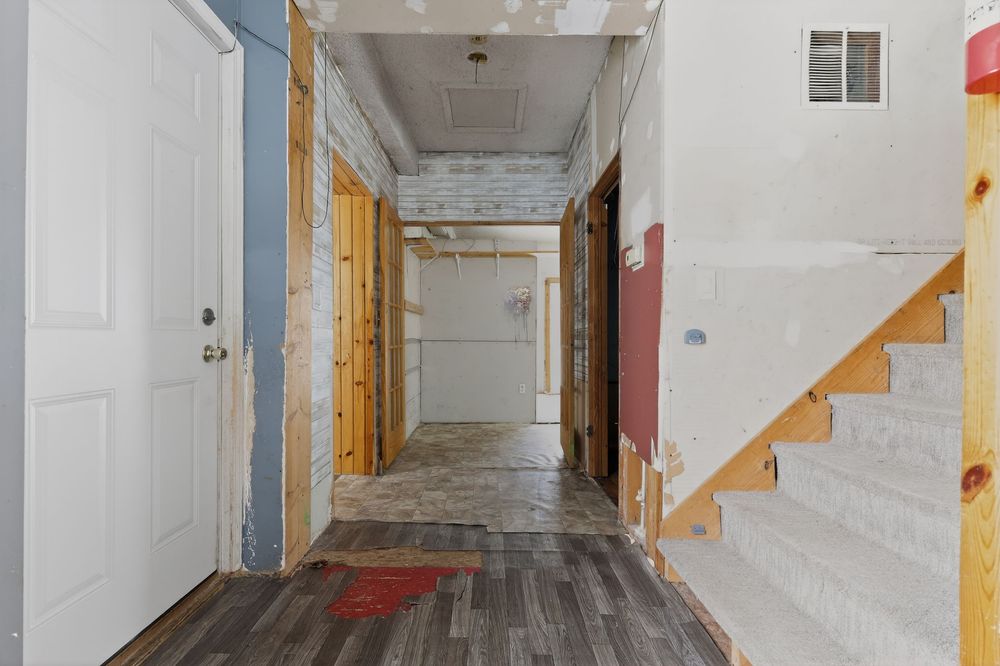 Unfinished home interior hallway under renovation with wood framing, drywall, and staircase.