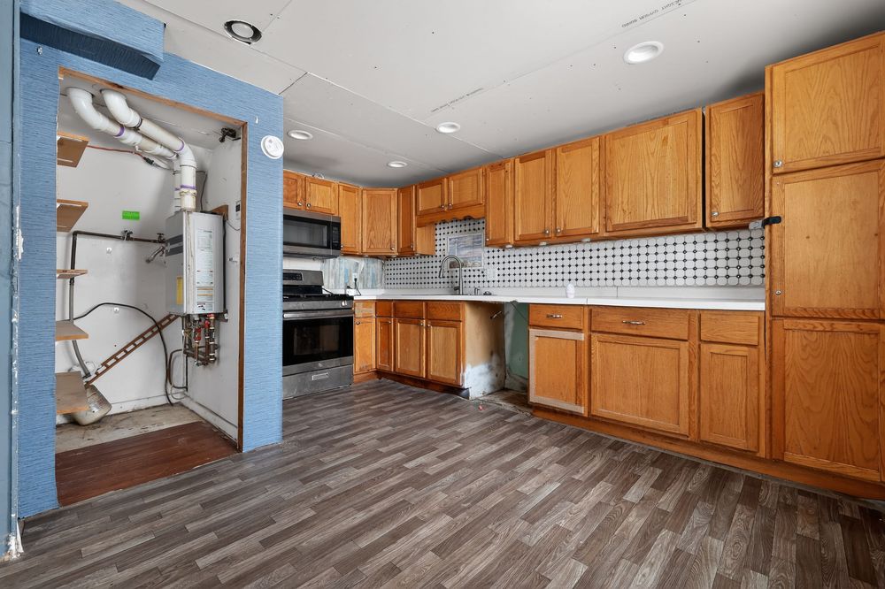Kitchen with oak cabinets, dark hardwood floors, stainless appliances, and brick backsplash.