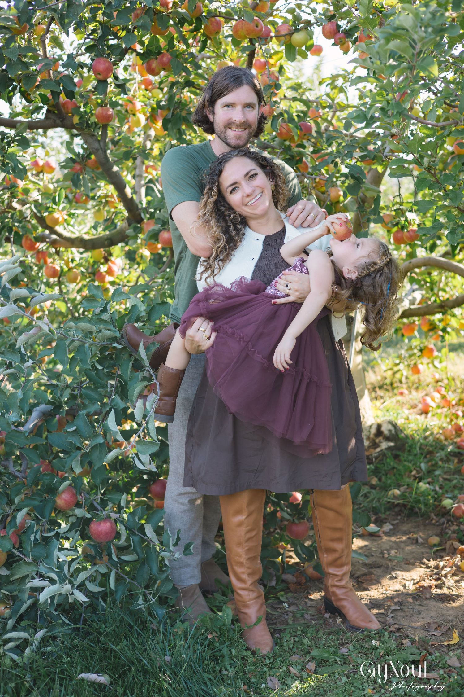 A couple enjoys a romantic moment while apple picking in an orchard during autumn.