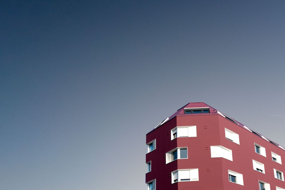 Photographie architecturale Morbihan – immeuble contemporain rouge en contre-plongée ciel dégagé