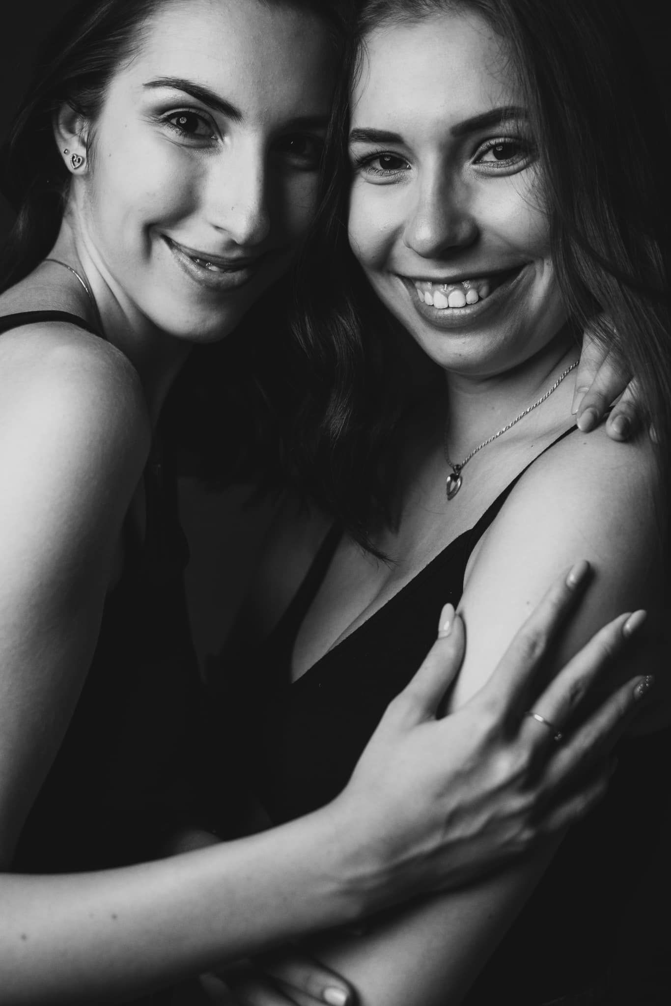 Black and white intimate portrait series showing tender embrace and joyful expressions in moody lighting.