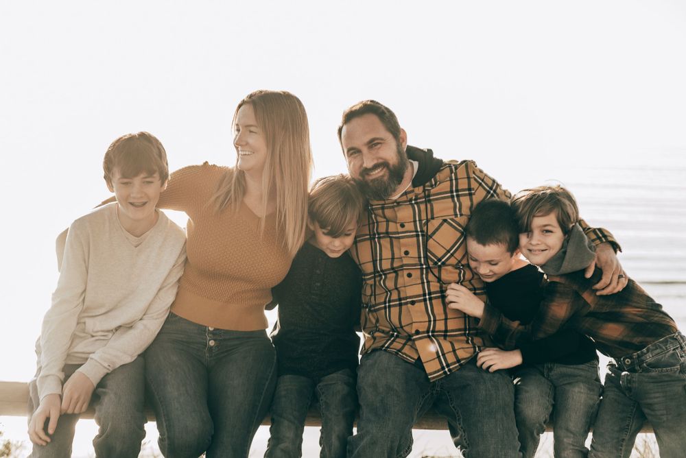 Family sitting close together on beach during golden hour.