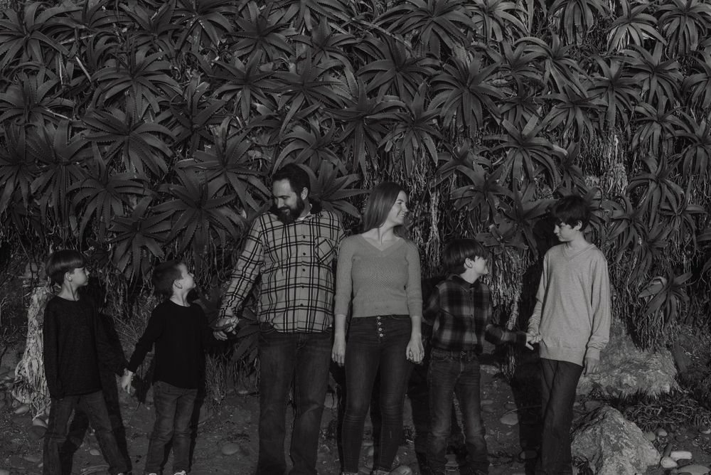 Group photo of people standing against a wall of dark foliage.