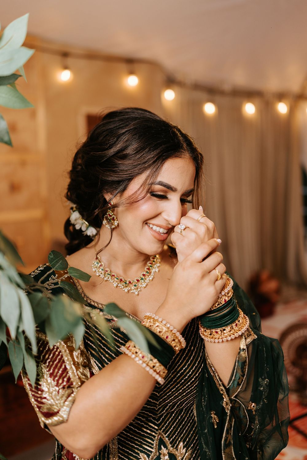 Emotional moments captured at an Indian wedding celebration with decorative lighting and traditional jewelry.
