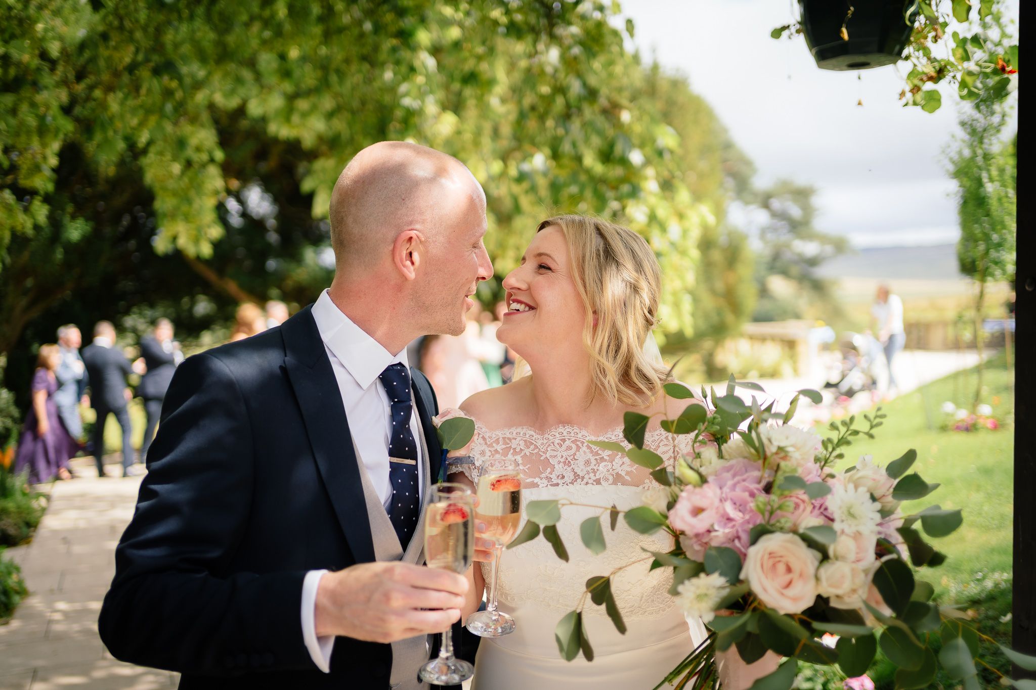 Romantic garden wedding portraits with pink floral arrangements and natural greenery. Woodhill Hall.