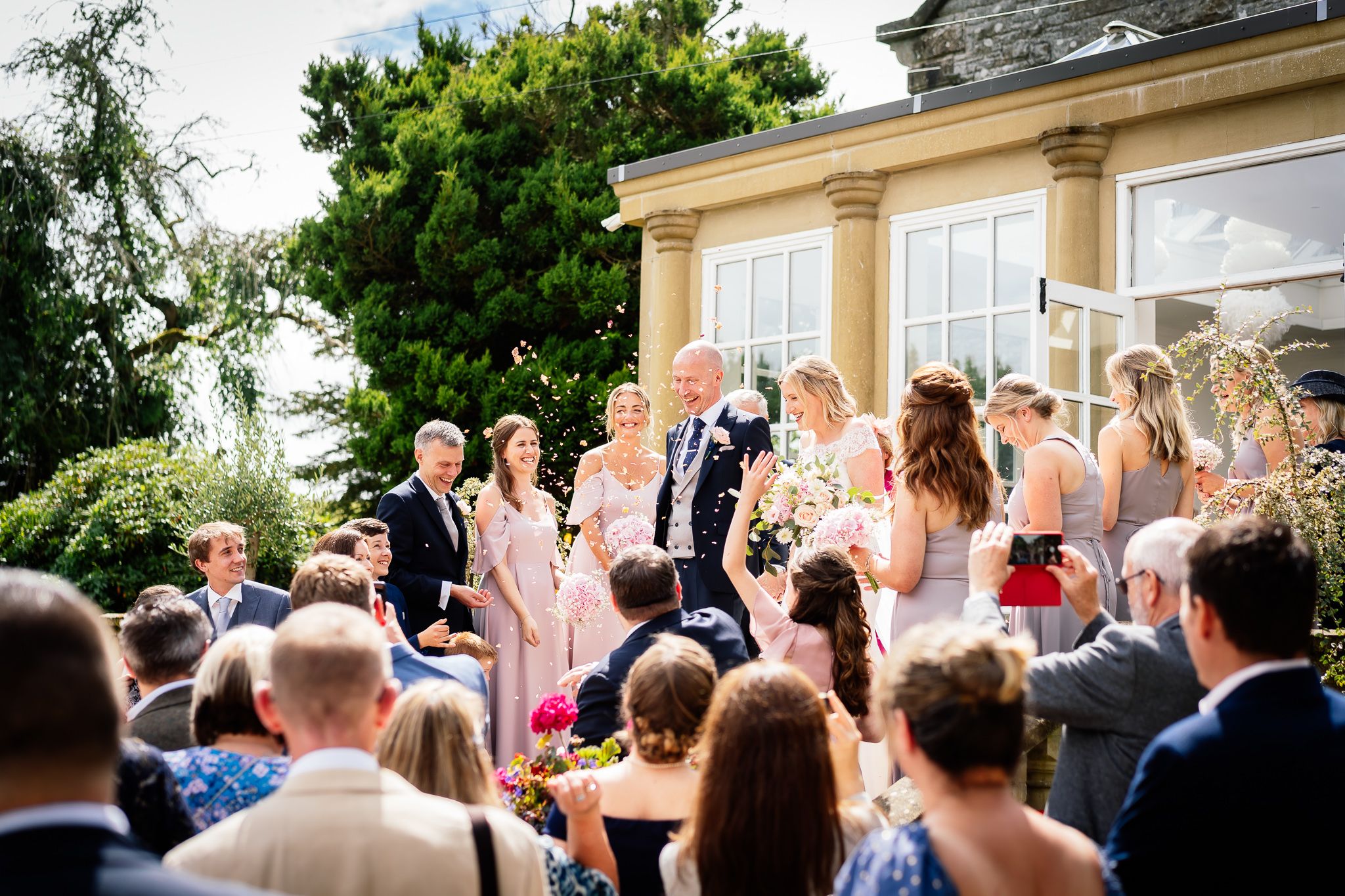 Wedding guests gather outdoors on a sunny day to celebrate the special occasion. Woodhill Hall.