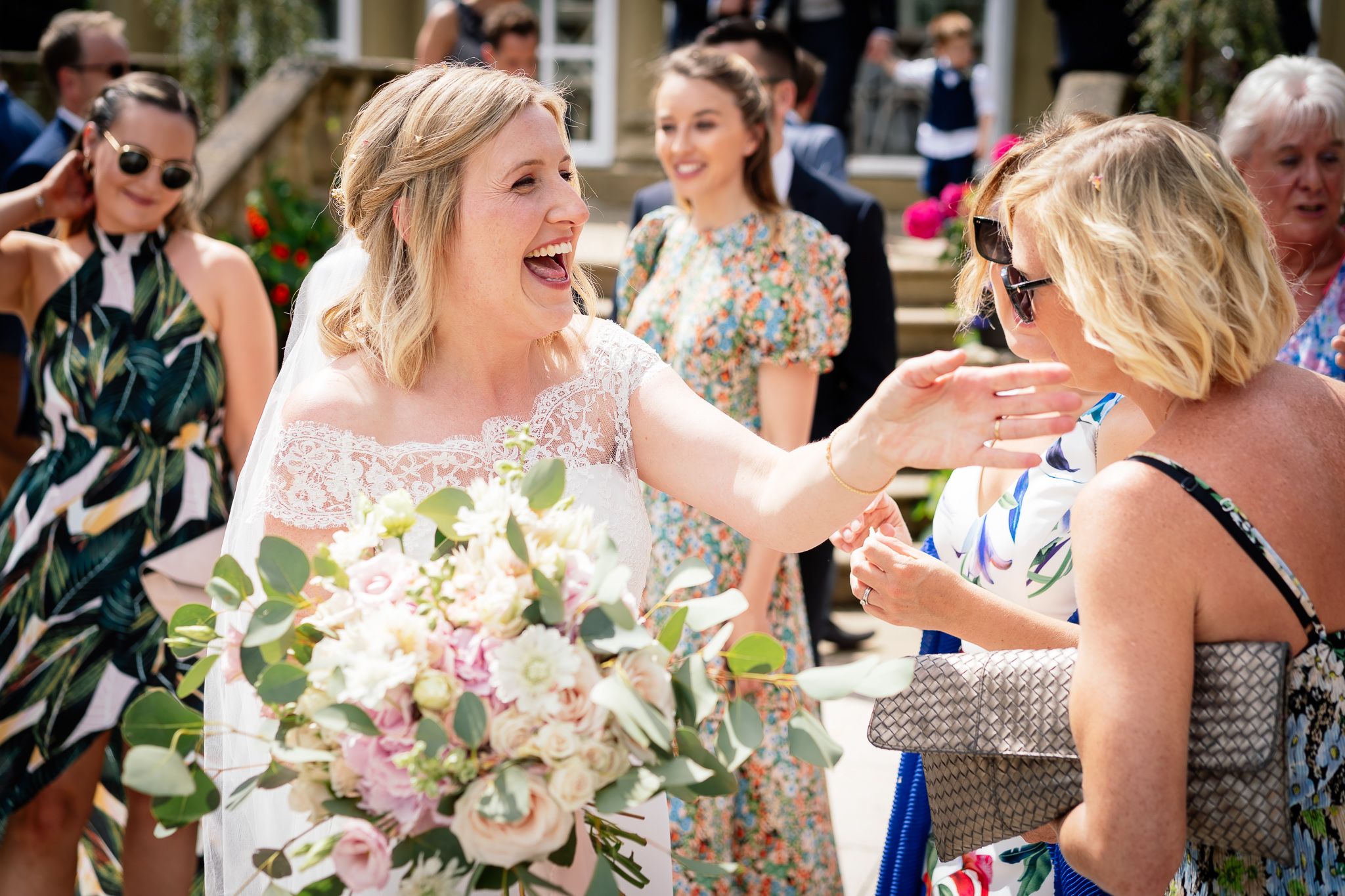 Wedding guests enjoying an outdoor reception with pink floral centerpieces. Woodhill Hall.