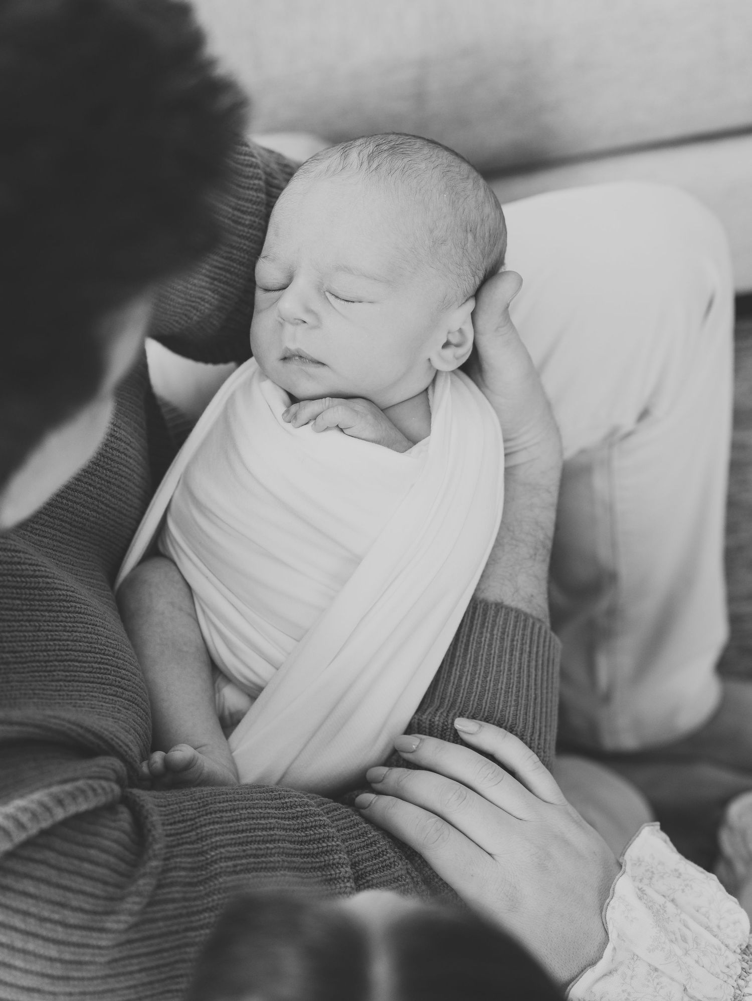 Mother and father cradling baby by window light, Monmouth County newborn photographer.