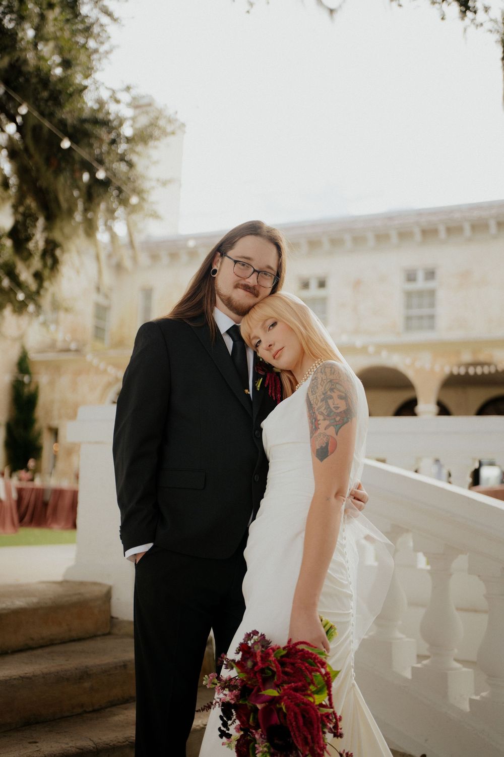 A romantic wedding couple shares a candid moment together on a sunlit terrace with white balustrades.