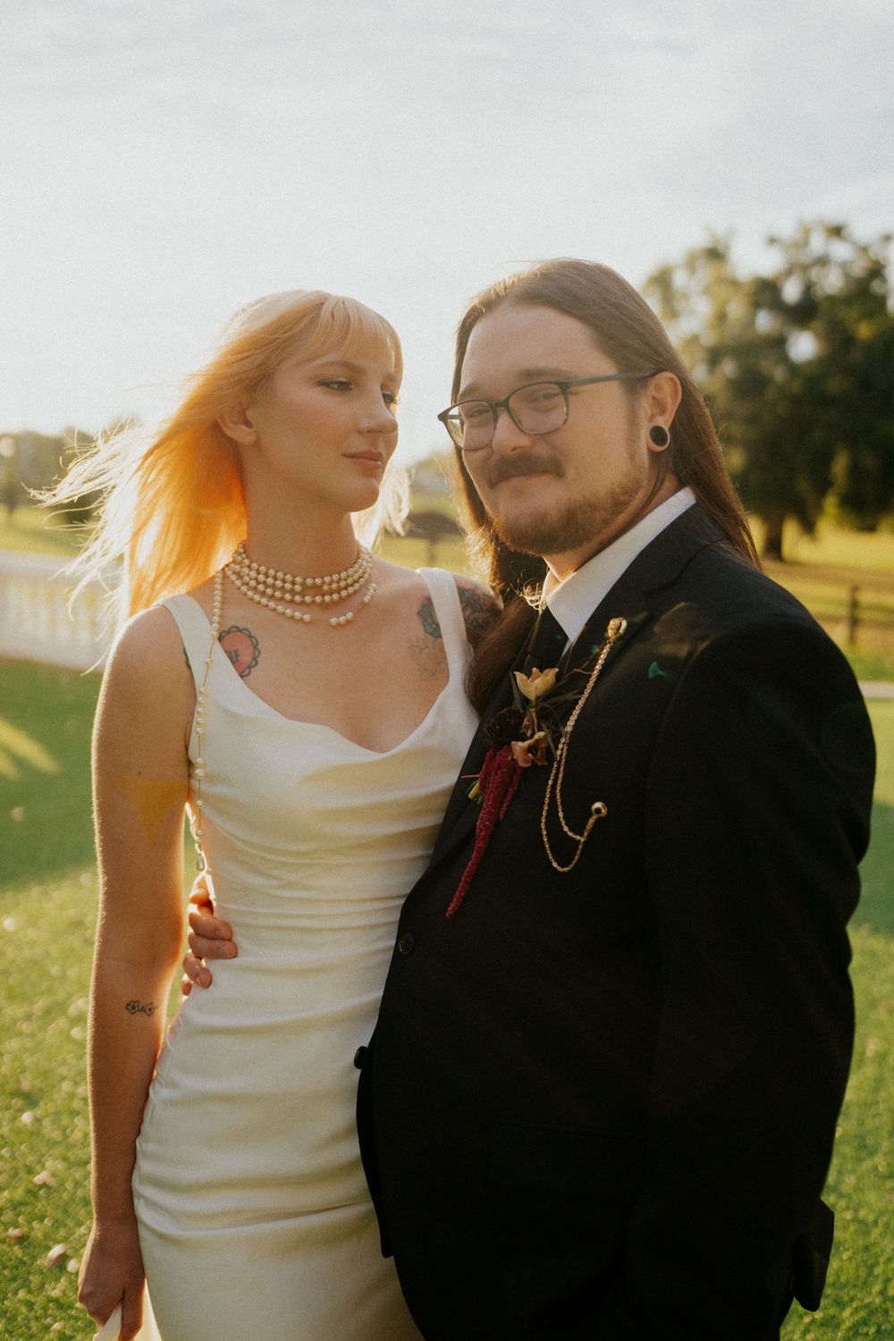 A romantic wedding couple embraces in a sunlit outdoor setting during golden hour.