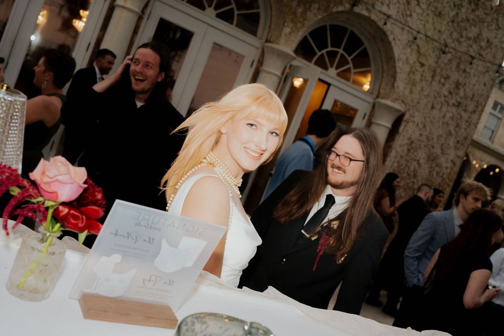 People celebrating at an elegant indoor event with brick walls and arched windows.