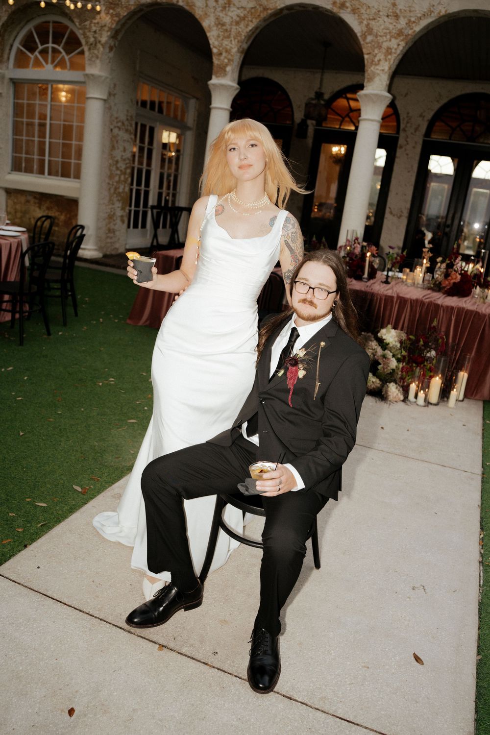 A wedding couple shares intimate moments under stone archways at an elegant venue reception.