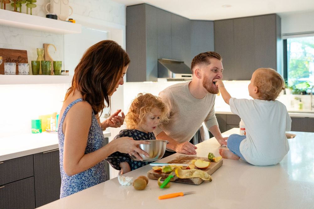 Family preparing healthy food together at a modern kitchen counter with natural lighting.