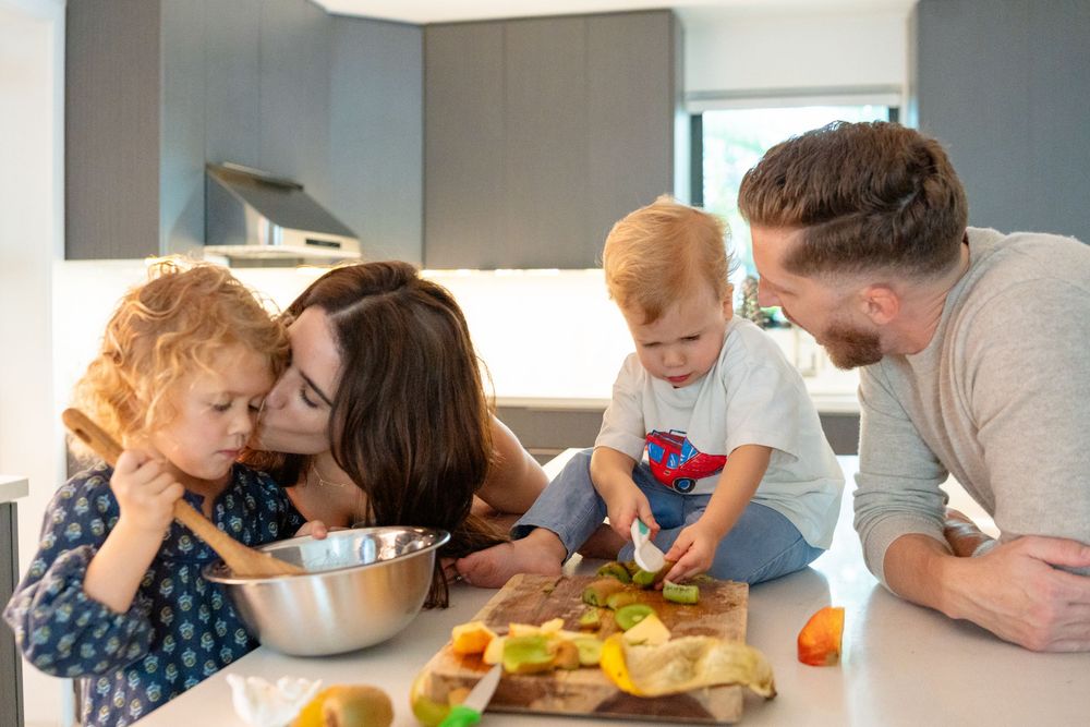 Family bonding while preparing fresh ingredients together at their kitchen island.