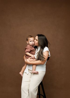 A tender moment captured in a series of brown-toned studio portraits showing affectionate embraces against a warm backdrop.