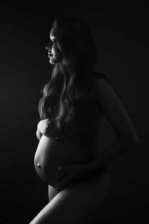 A black and white artistic maternity photo series showing silhouettes of a pregnant woman's belly in dramatic lighting.