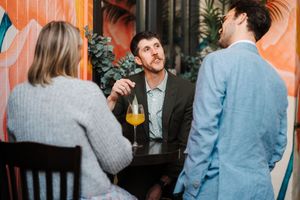 Group of guests mingling at an elegant cocktail reception with orange-tinted lighting.