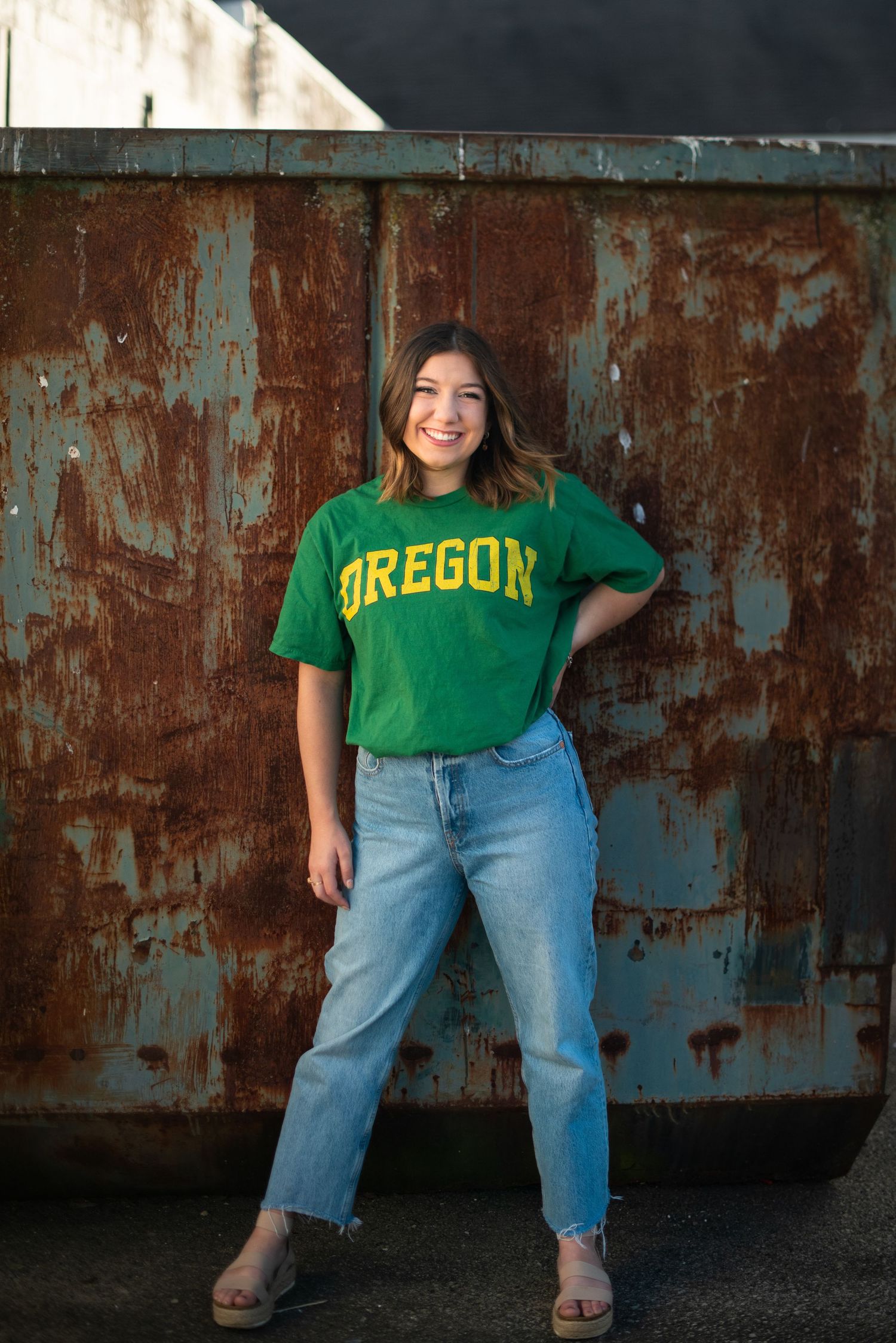 A series of four casual photos showing someone wearing an Oregon university t-shirt and blue jeans against a rustic wall.